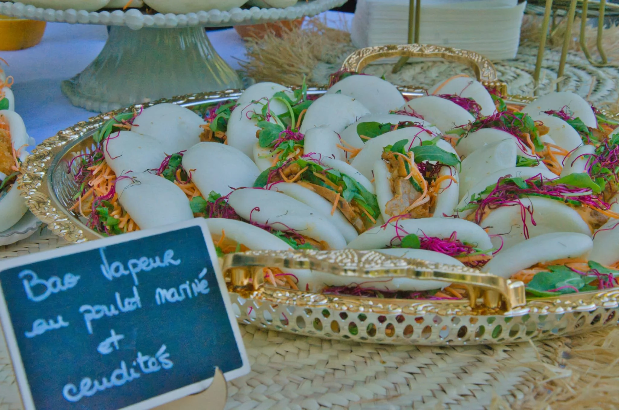 Plate de tacos avec du poulet, garnitures de légumes et herbes, présentée sur un plateau argenté dans une ambiance de marché ou de buffet