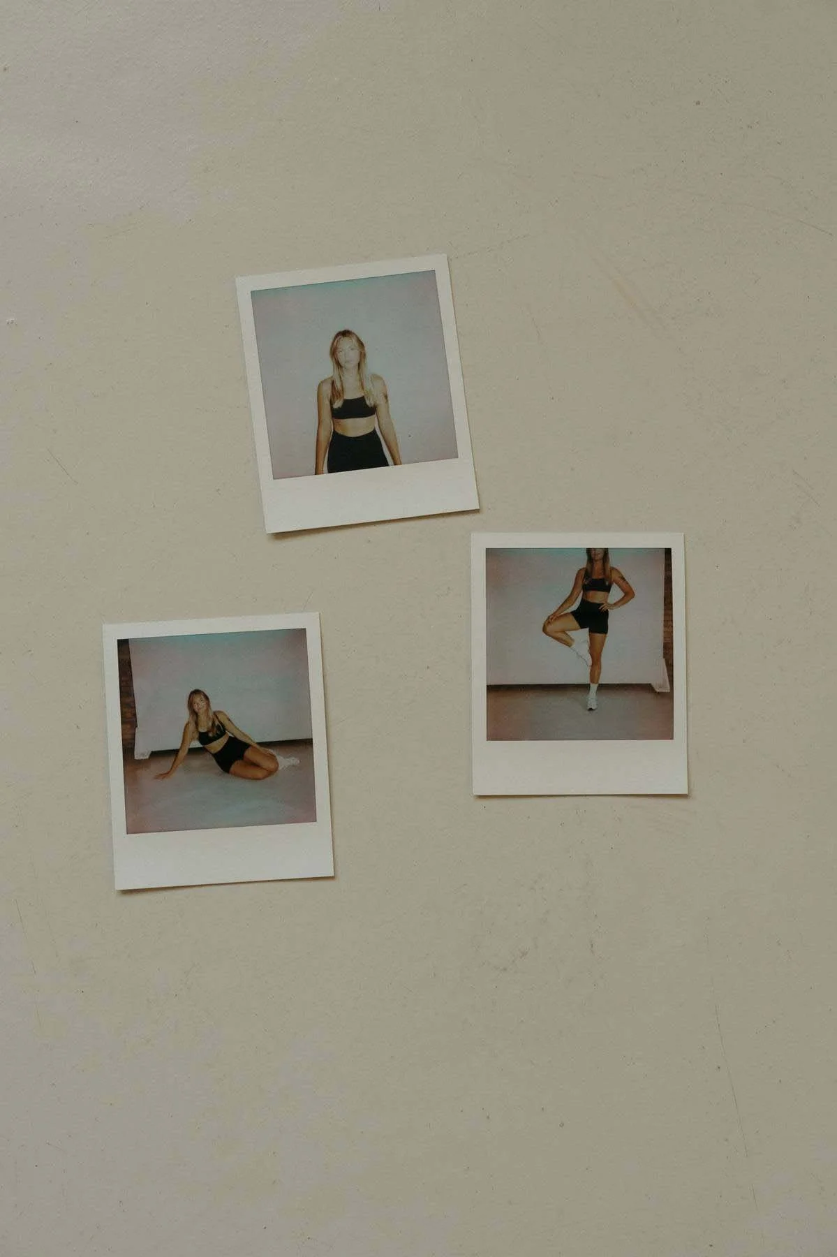 Three Polaroid photos of a woman in athletic clothing, showing her in different poses against a plain wall and floor.