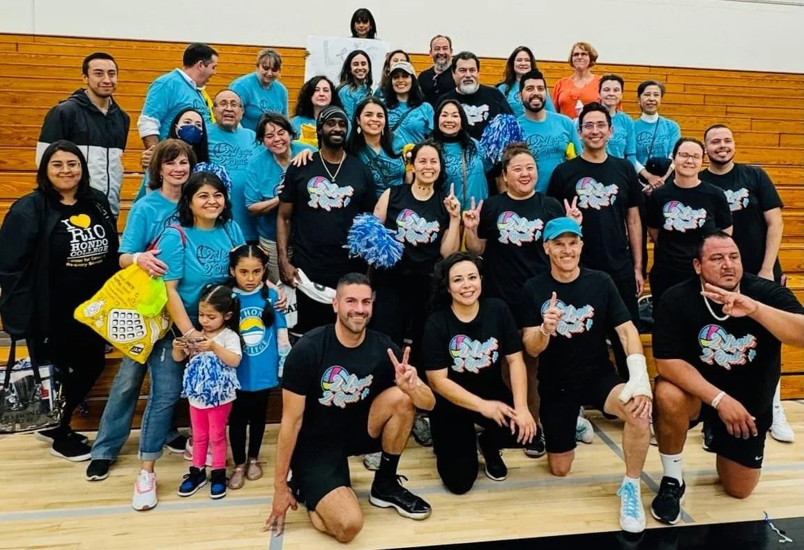 Group of people in a gymnasium, some wearing matching shirts with a parachute logo, posing for a group photo.