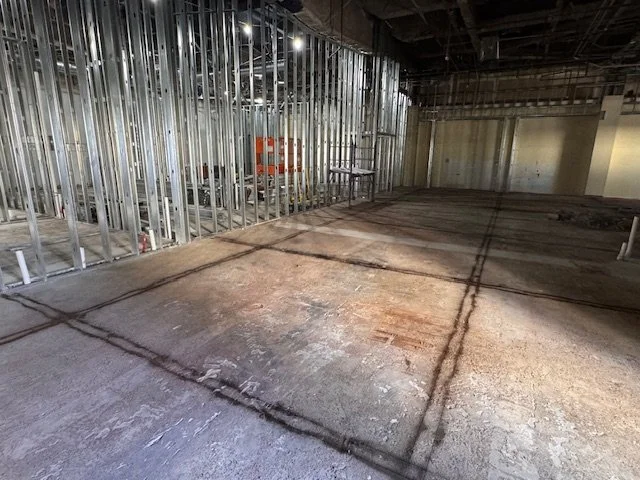 Interior of a building under construction with exposed metal framing and concrete floor.