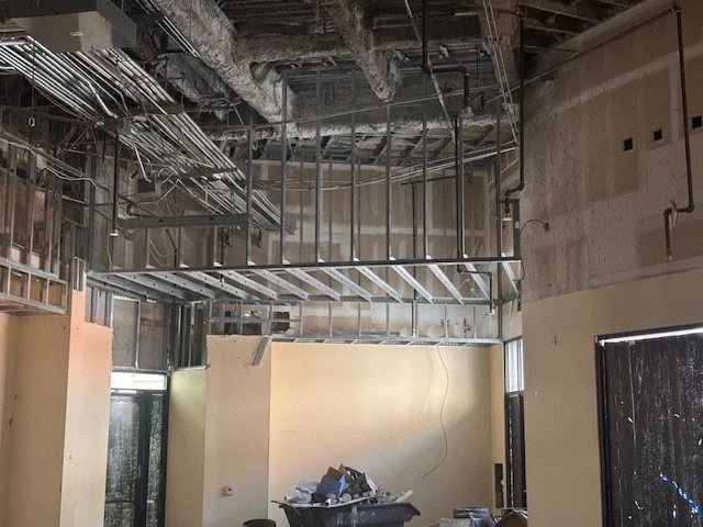 Interior of a building under construction with exposed metal framing, wiring, and unfinished walls.