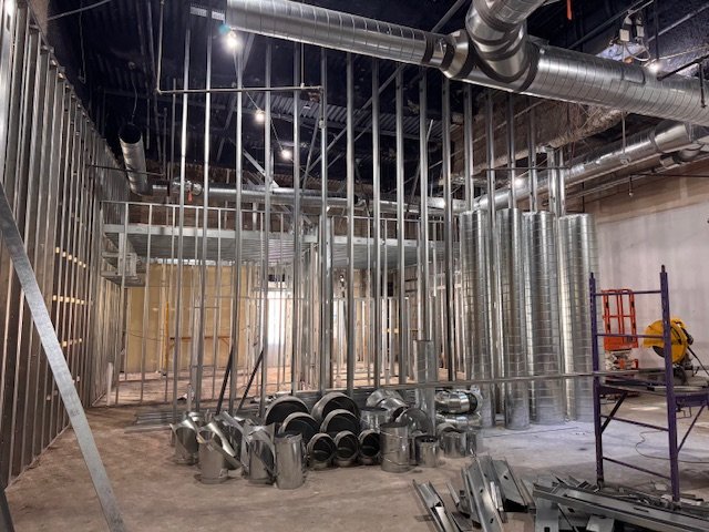 Construction site with metal framing, ductwork, and ventilation pipes in a building under construction.