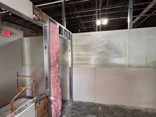 Interior of a construction site with metal framing, pink insulation, and unfinished walls.