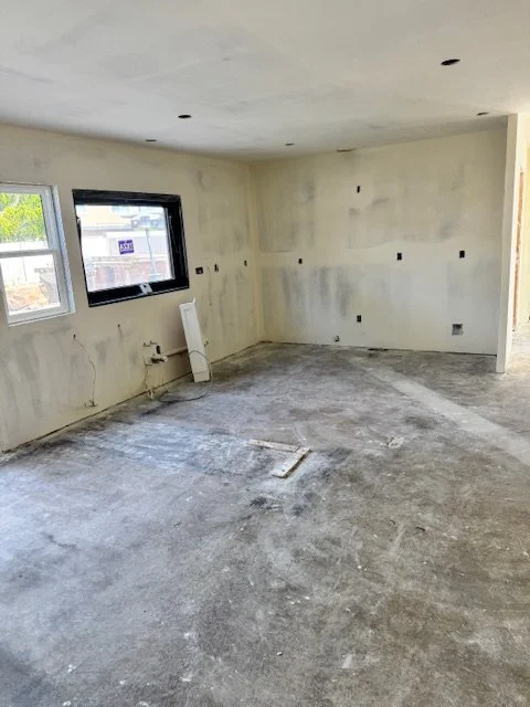 Room under construction with unfinished walls, exposed wiring, and a rough concrete floor.