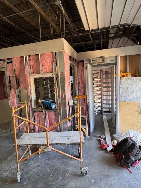 Construction site with partially built walls, pink insulation, an elevator shaft, and construction tools and equipment.