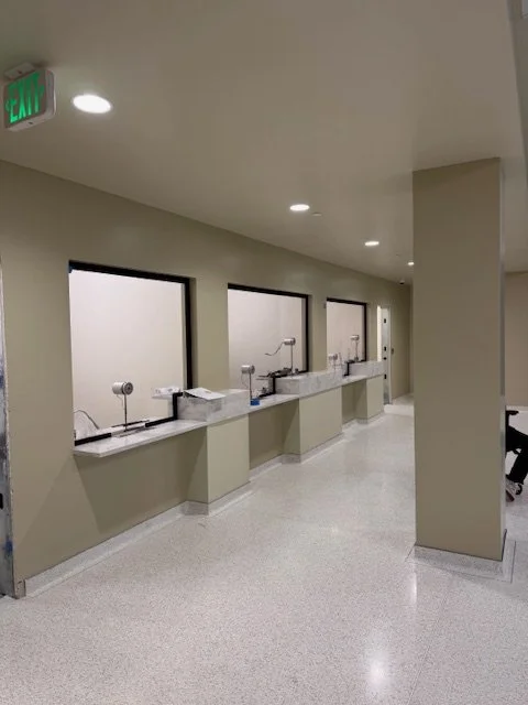 An indoor hallway with four selfie stations, each with a tablet, lights, and a small shelf, separated by partition walls.
