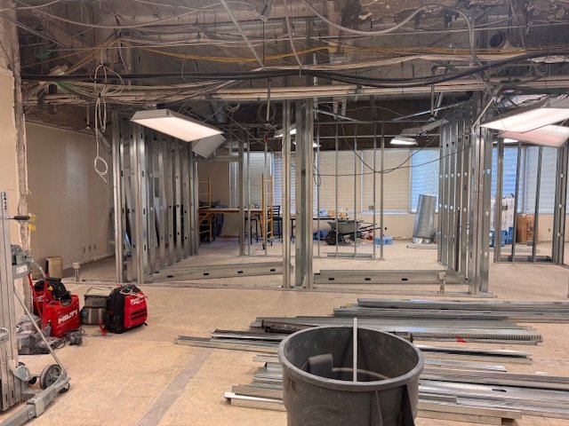 Construction site with metal framing, exposed wiring, construction tools, and materials in progress.