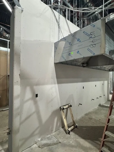 Construction site with drywall, metal framing, and tools nearby.