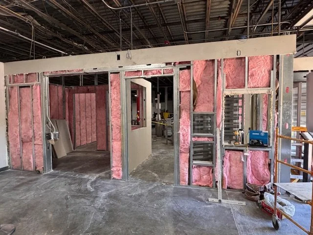 Construction site with interior walls framed with pink insulation and some drywall panels installed