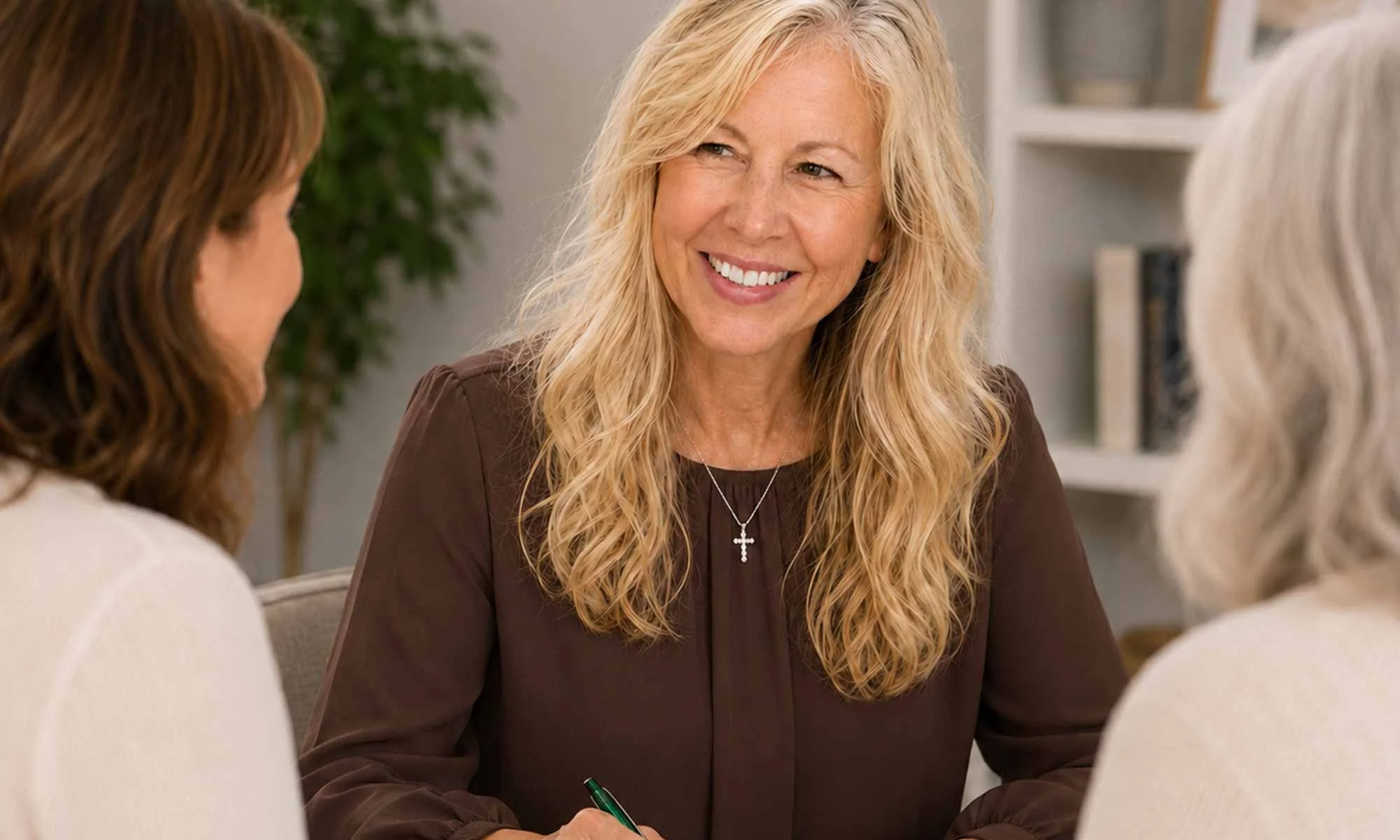 Dr. Sharon May smiling, during a conversation with two other women in an indoor setting.
