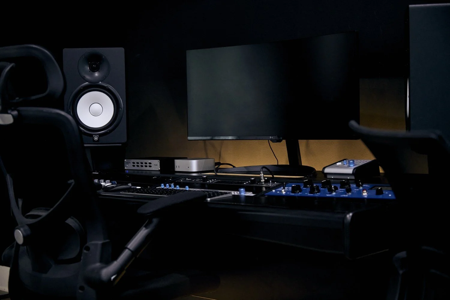 Music studio room with computer monitors, studio speakers, and audio mixing equipment.