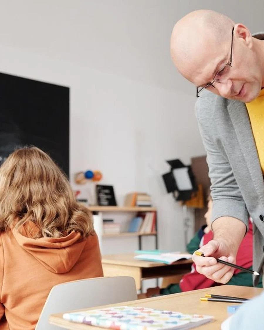 A teacher handing out pencils to students in a classroom.