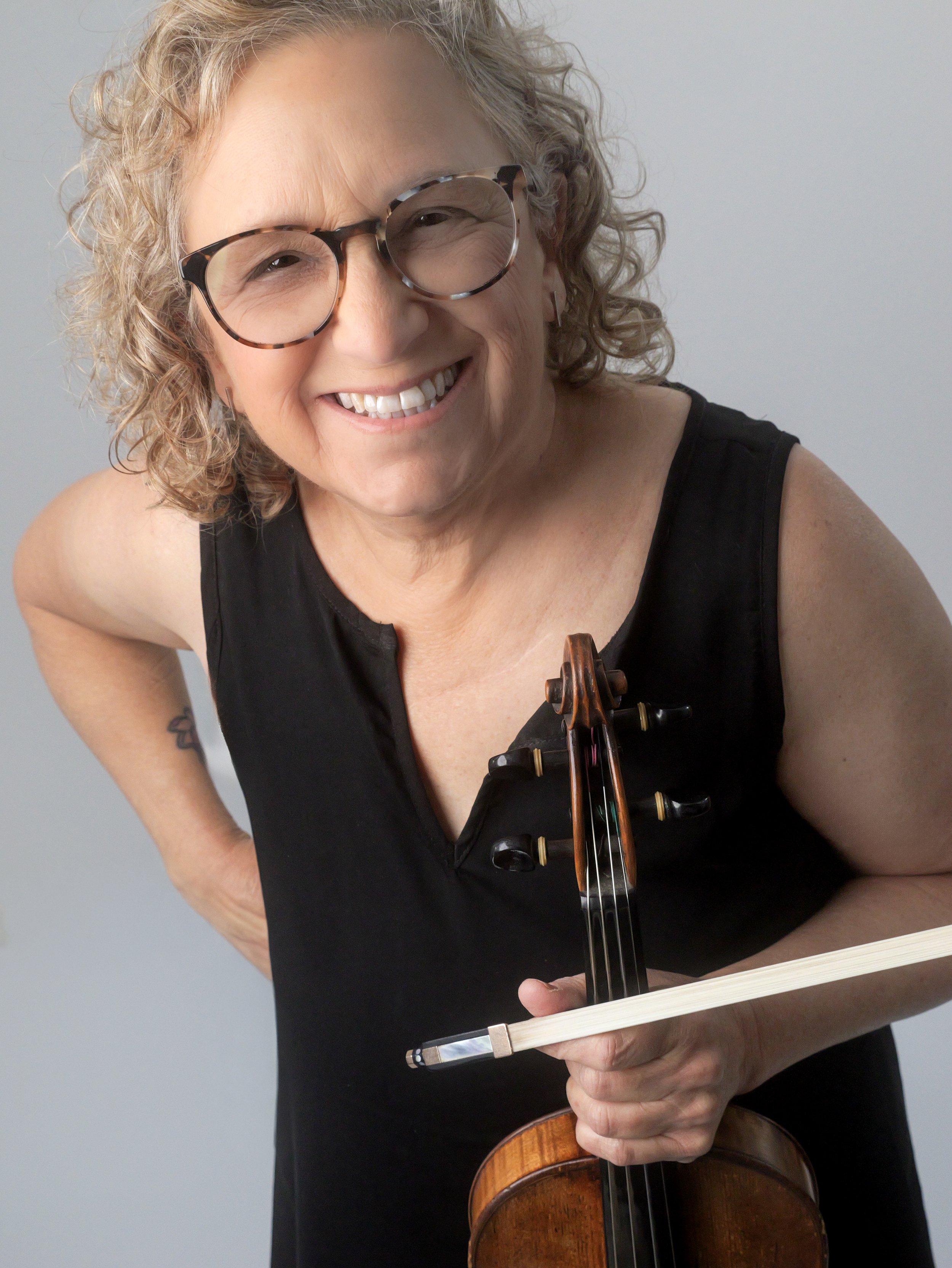 Smiling woman wearing sunglasses and holding a violin and bow