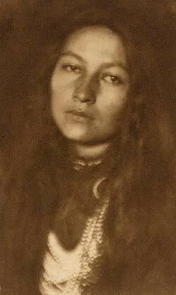 Sepia-toned vintage portrait of a woman with long dark hair wearing a necklace and light-colored blouse