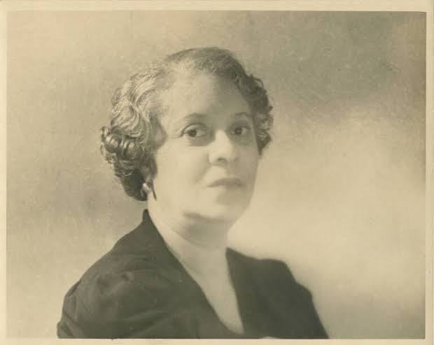 Black-and-white vintage portrait of a woman with short, wavy hair wearing a dark dress.