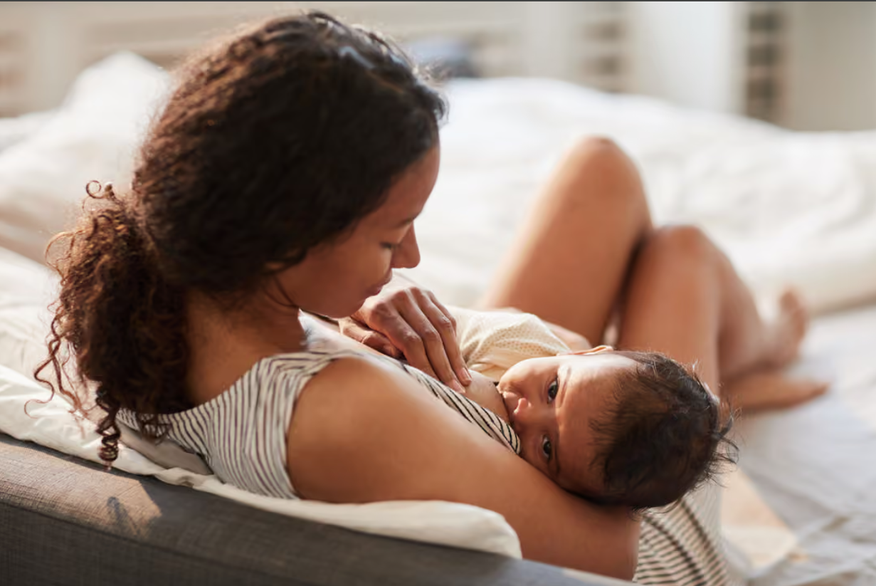 Woman breastfeeding a baby on a bed.