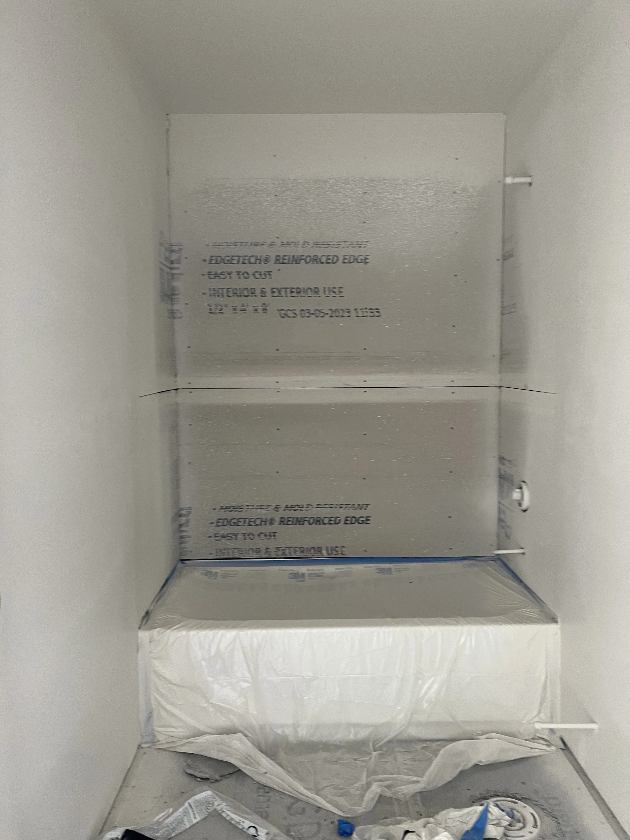 Empty painted interior space of a small box or cabinet with a plastic bag and some debris at the bottom.