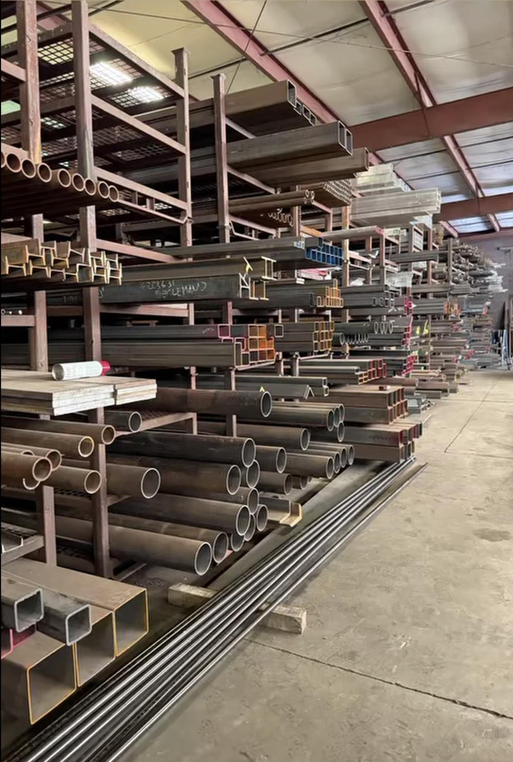 Interior of a hardware store with steel pipes and metal materials stored on industrial racks.