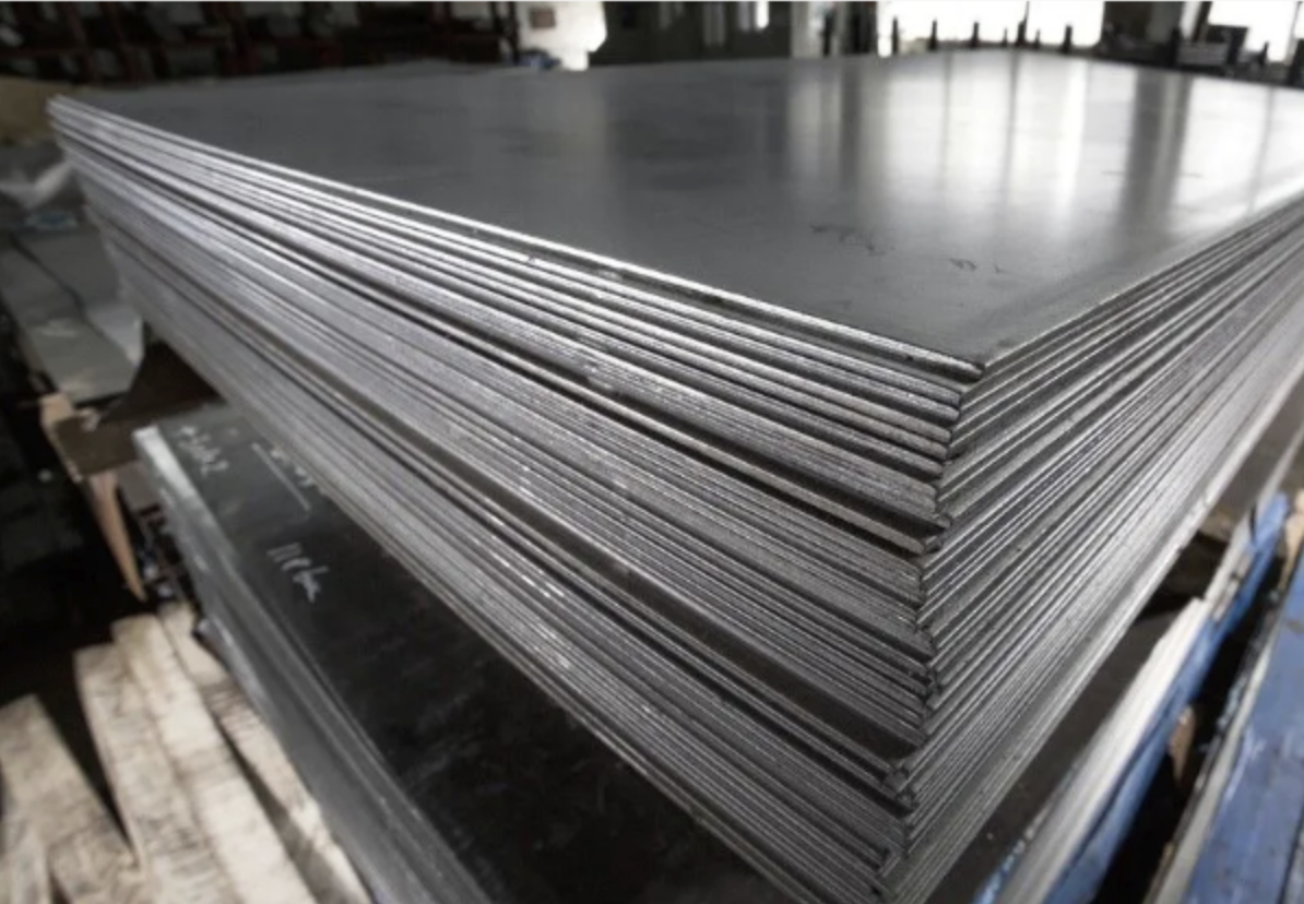 Stack of metal sheets or plates stored on a table or work surface.