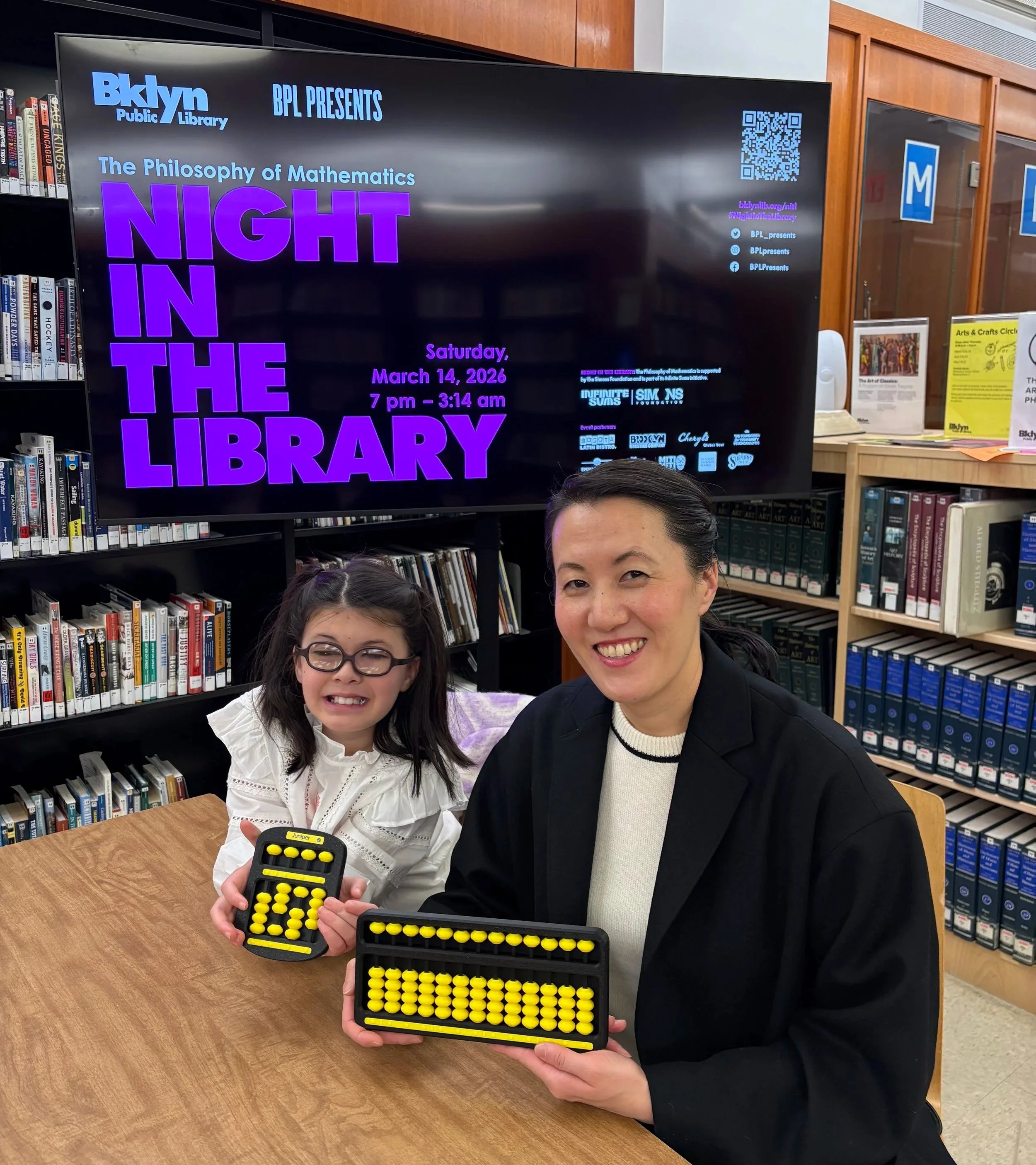 Juniper Eisenberg and Chi-Hoon Kim holding Braille Forward's 3D-Click Abacus and 13-Rod Speed Click at Brooklyn Public Library's The Philosophy of Mathematics Night in the Library.