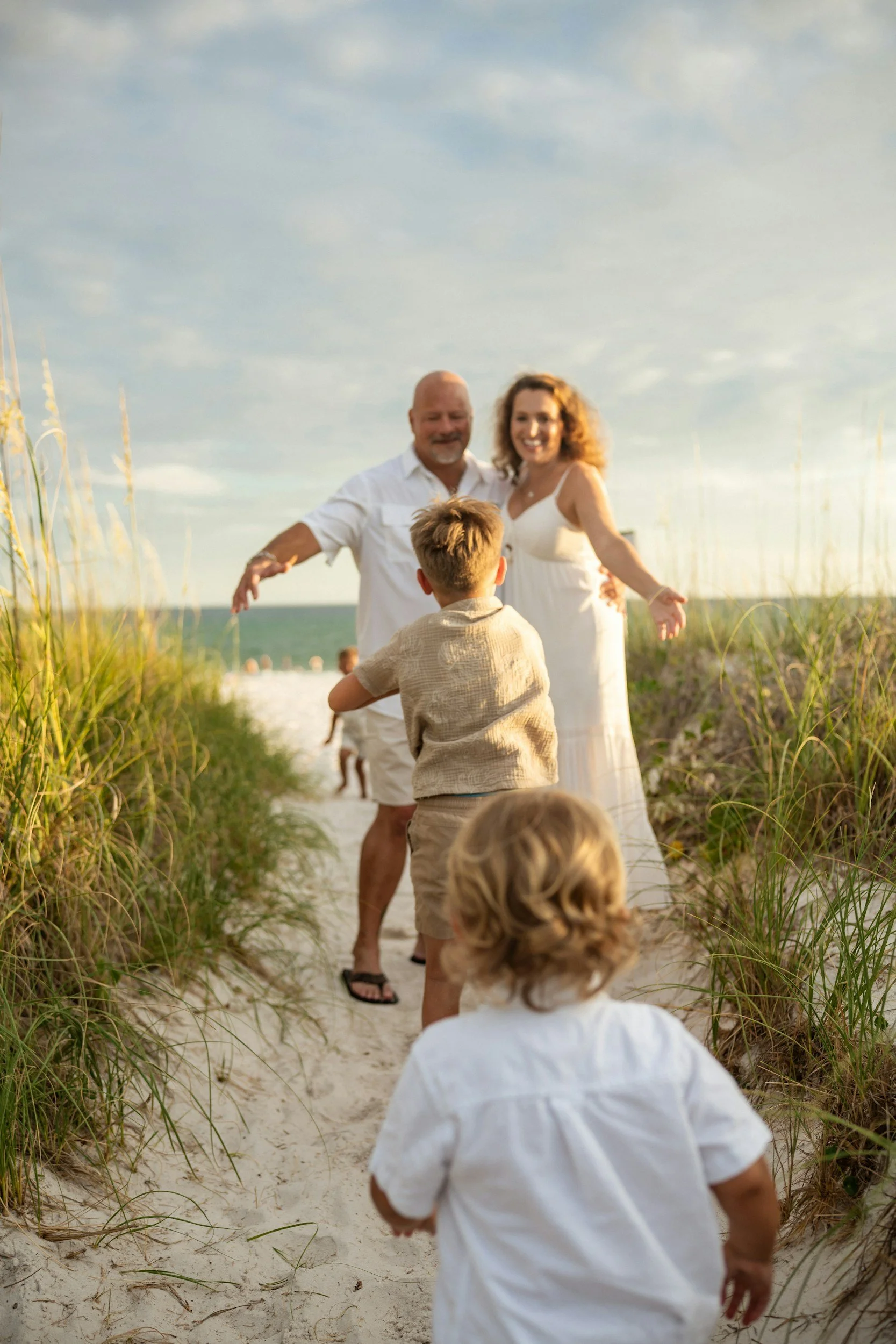 Grandparents on a multi-generational family vacation awaiting their running grandchildren to take them to the beach.