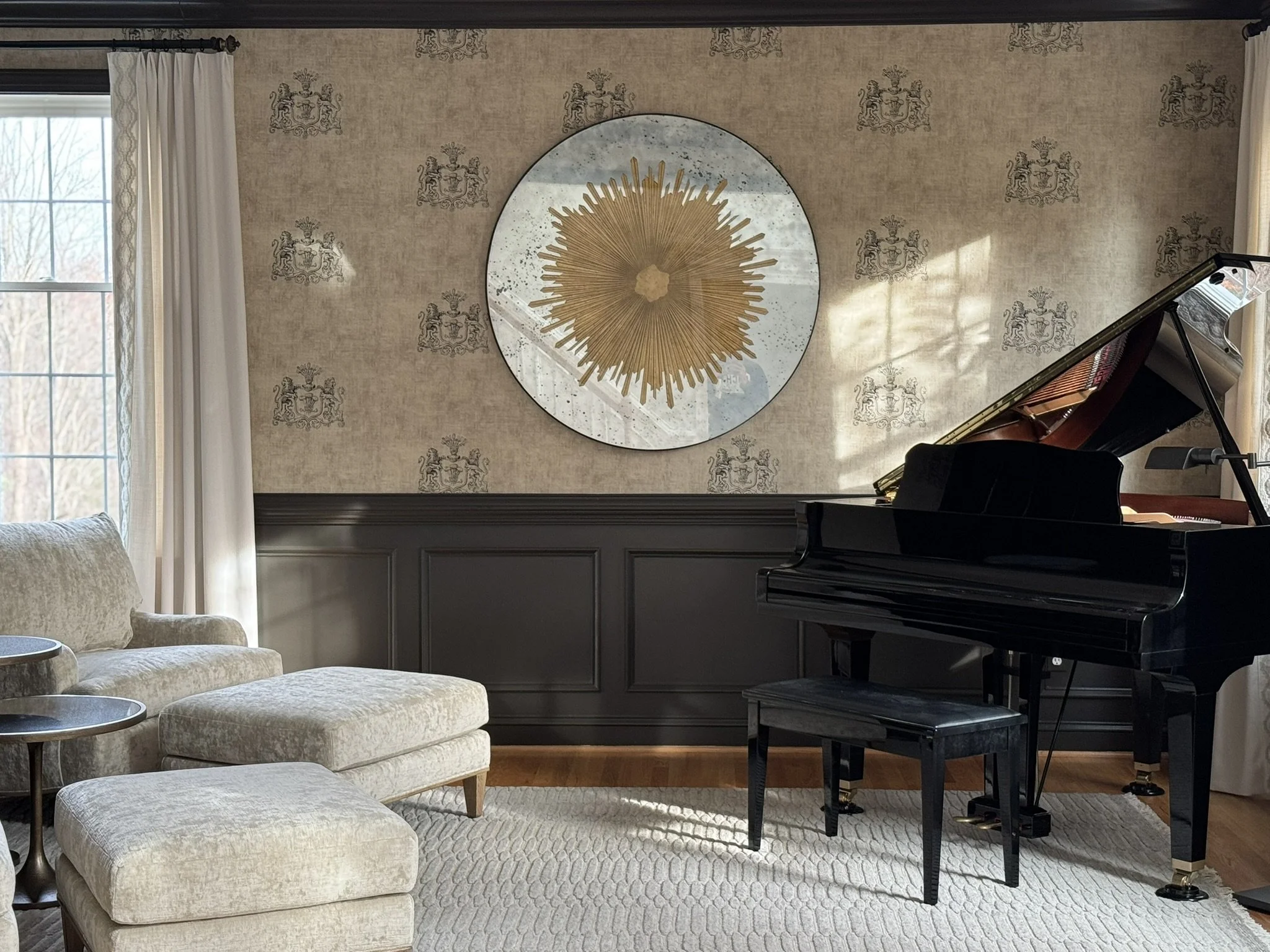Living room with patterned wallpaper, large window with white curtains, cream-colored sofa with matching pillows, black grand piano, and a beige textured rug.