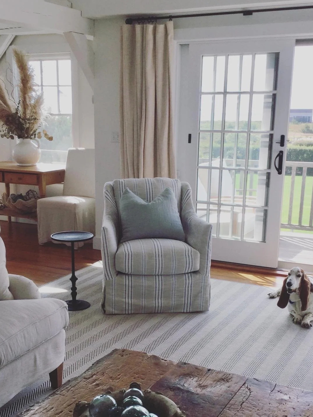 Living room with a striped armchair, a pillow, sliding glass door, and a beagle puppy lying on the carpet.