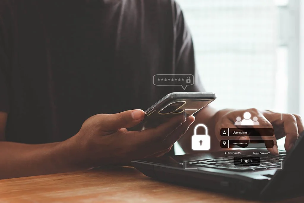Person using a smartphone and laptop for online login with digital security icons and login fields.