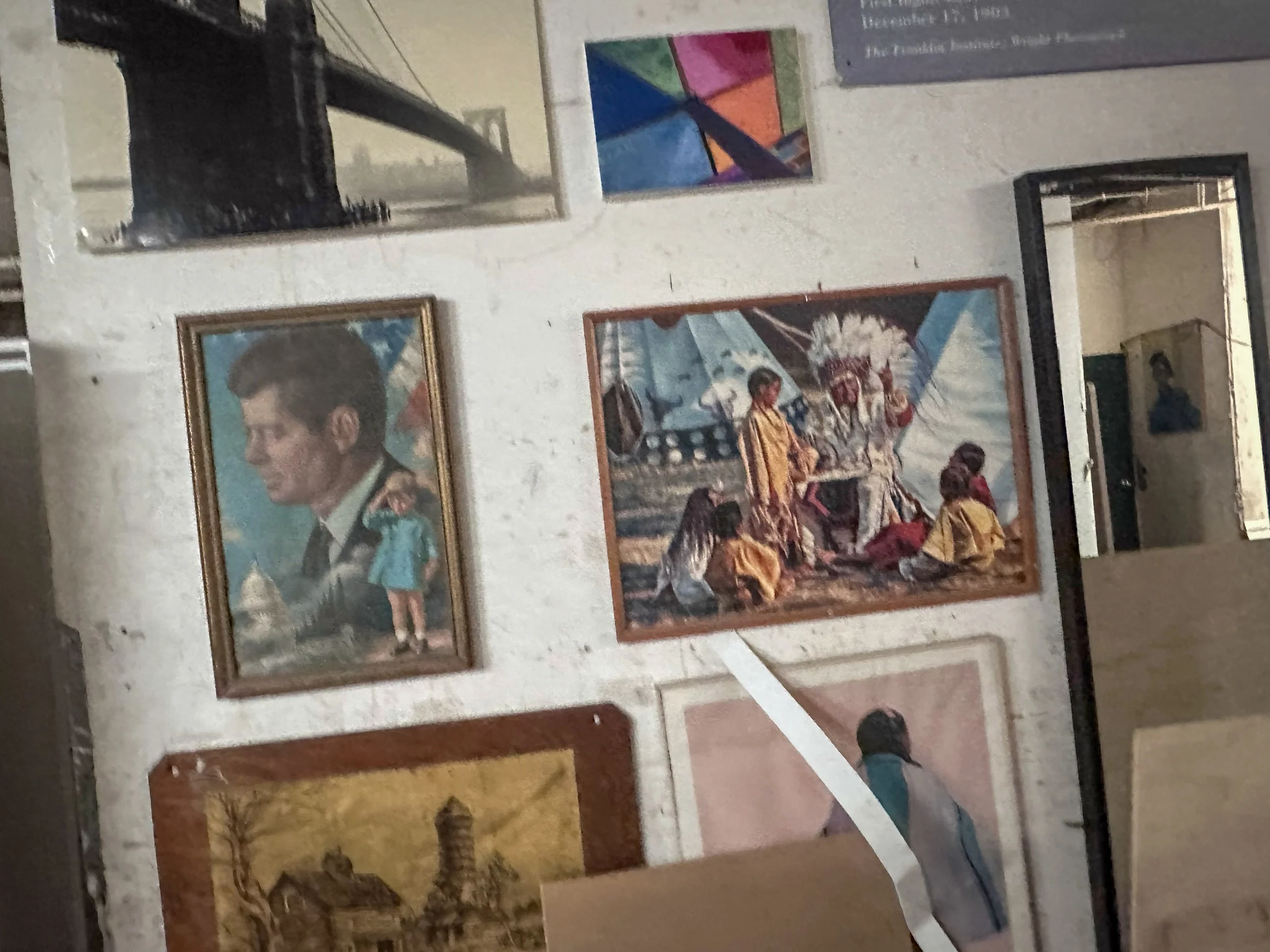 A gallery wall displaying various framed posters and artwork, including a portrait of Elvis Presley, surreal and pop art images, and vintage posters.