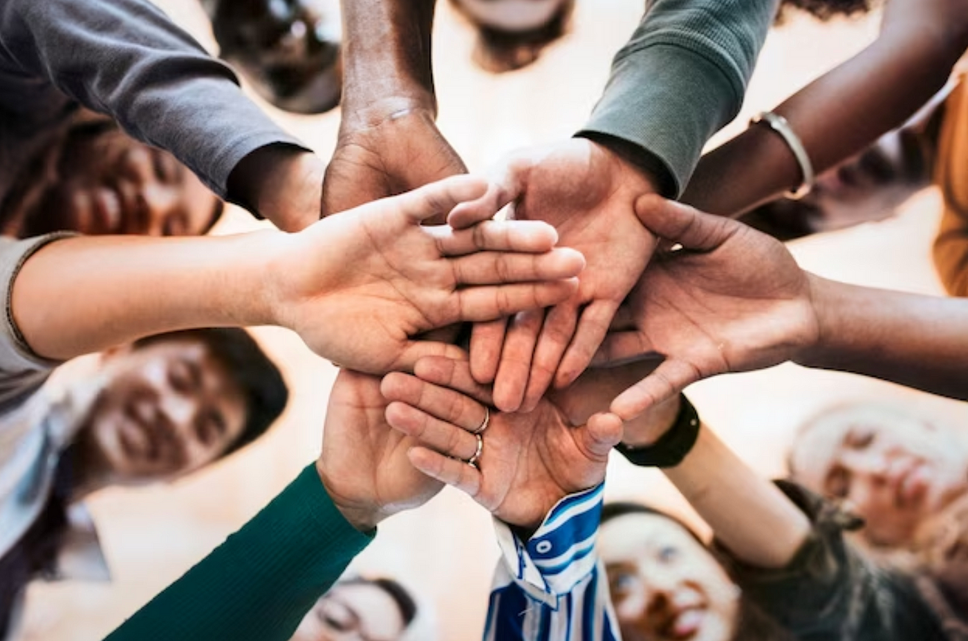 Group of diverse people putting their hands together in a gesture of unity.