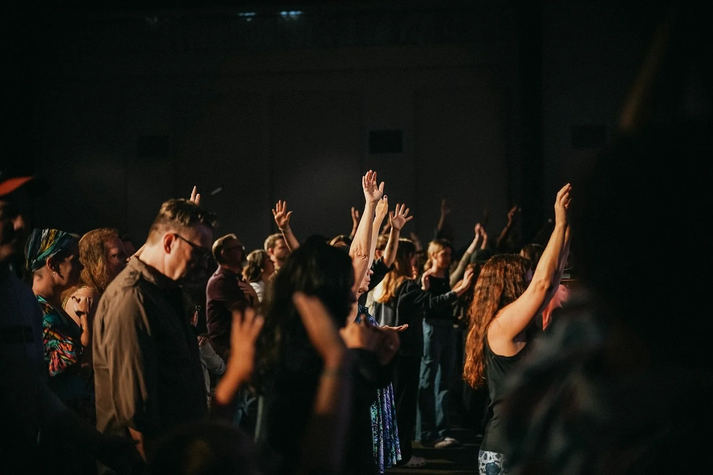 Crowd of people at a concert or event with many raising their hands.