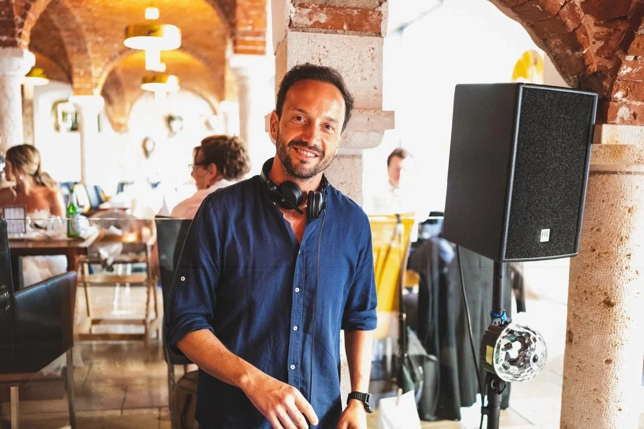 DJ Mister Wulff lächelt in stimmungsvollem Gewölbe-Ambiente mit Gästen