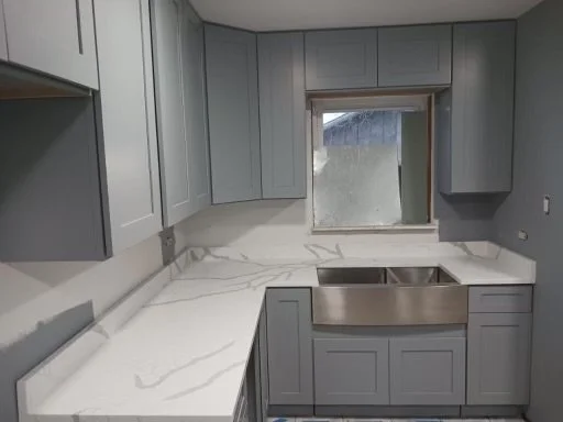 Kitchen with gray cabinets, white marble countertops, and a stainless steel sink under a small window.