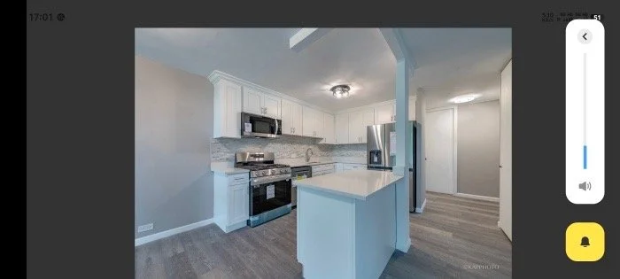 Modern kitchen with white cabinets, stainless steel appliances, and a small island with a white countertop.