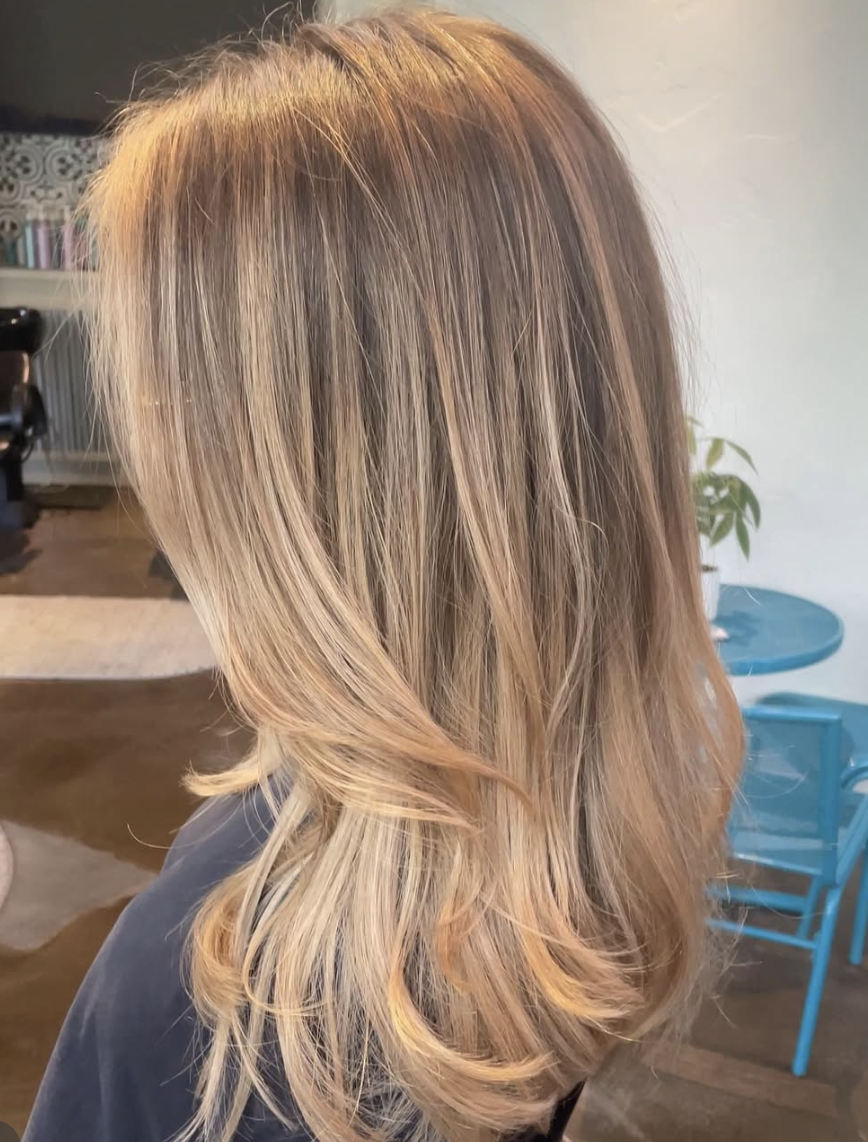 Long, layered, blonde hair with subtle highlights, styled in loose waves.