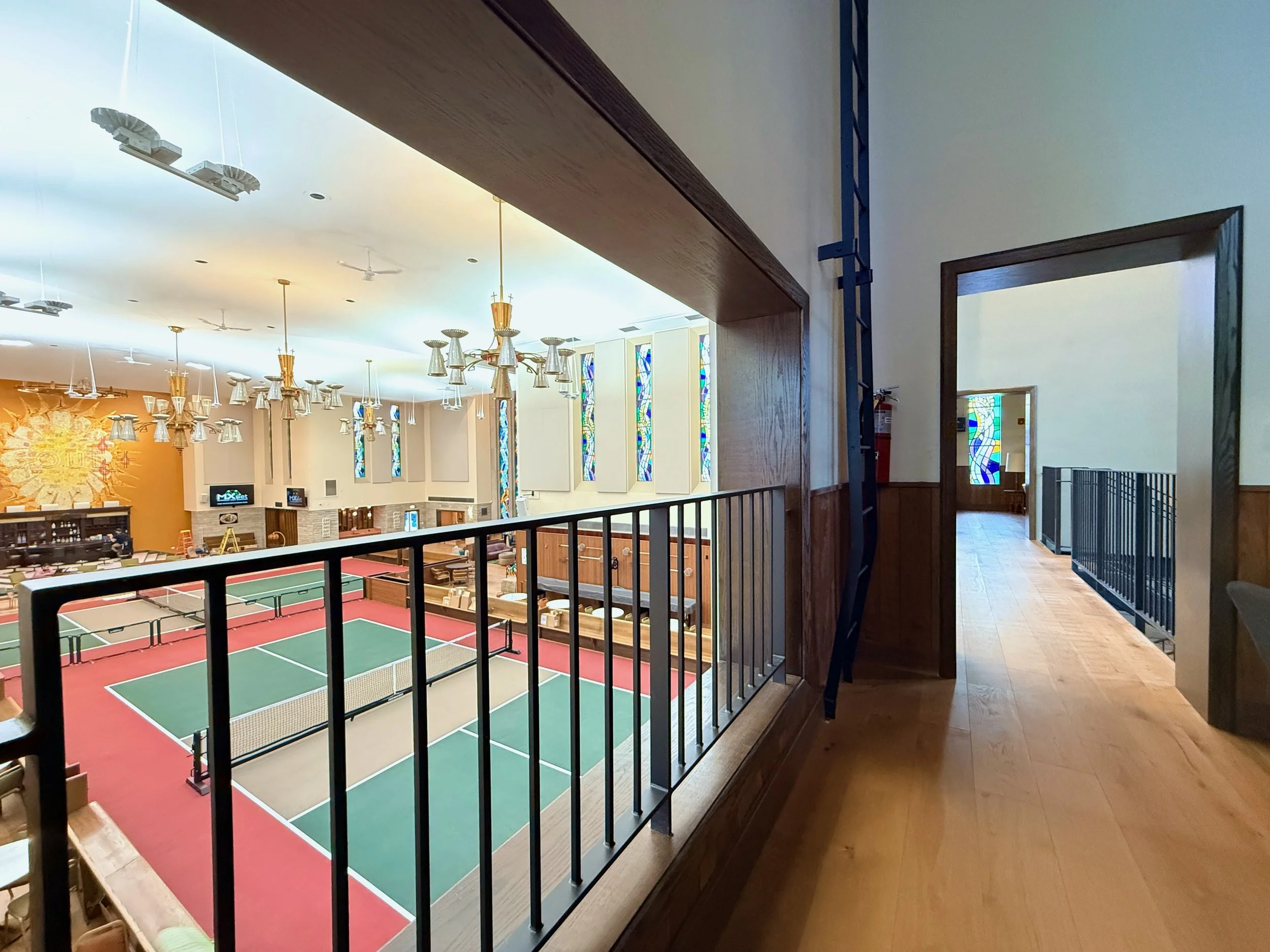 Indoor recreational facility with ping pong tables, seating areas, and large stained glass windows.