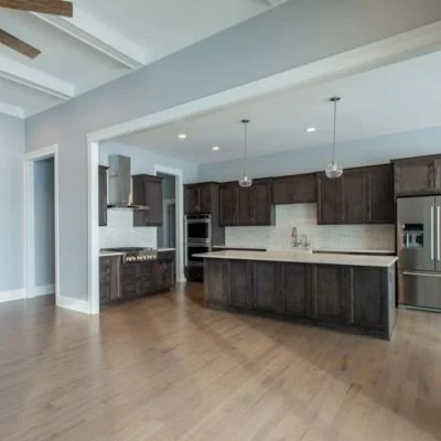 Empty modern kitchen with dark wood cabinets, stainless steel appliances, and a light-colored countertop.