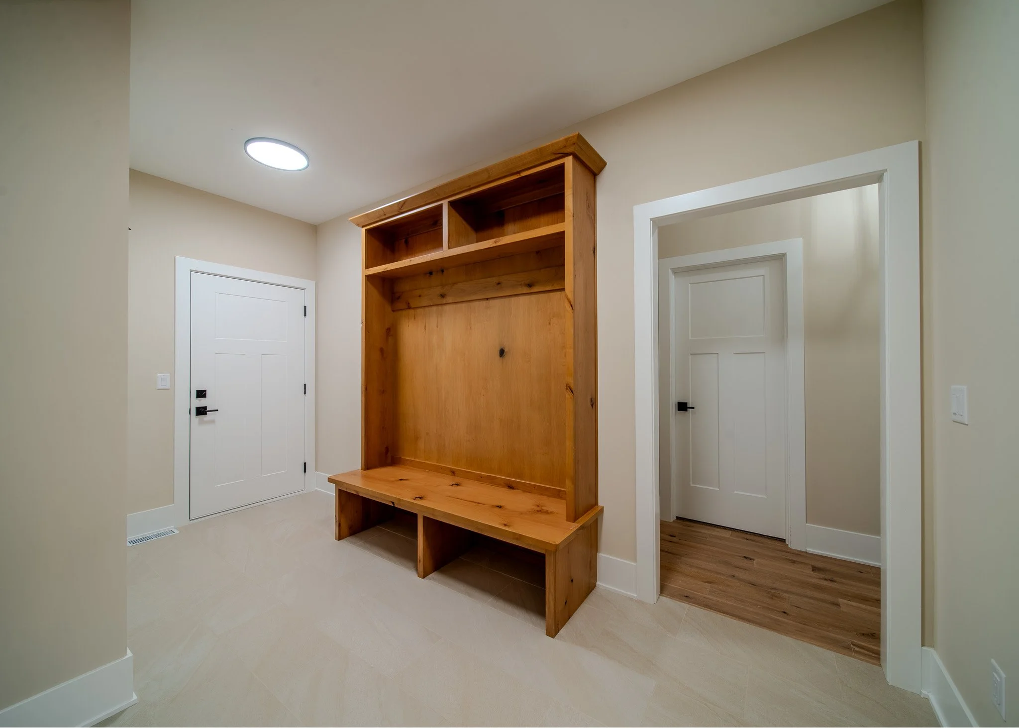 An interior space features a wooden structure with shelves against a beige wall, white doors, and a ceiling light.