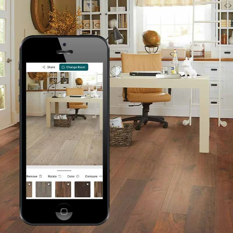 A home office with a white desk, tan office chair, and wall shelves, featuring decor like a globe, rabbit figurine, and books. A smartphone displays a photo editing app with a similar room image, showing flooring options.