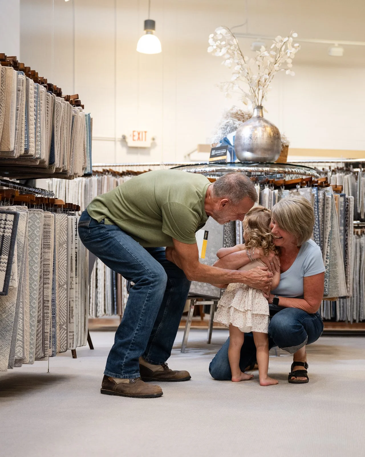 Family joyfully hugging inside a home improvement store, surrounded by fabric samples and home decor.