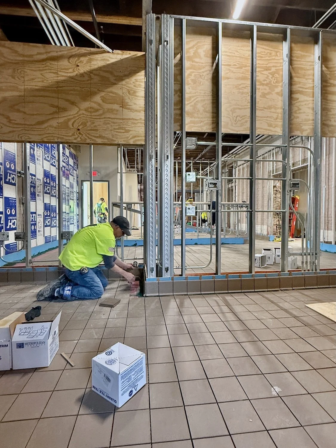 Construction workers installing flooring and wall framing in a building under construction.