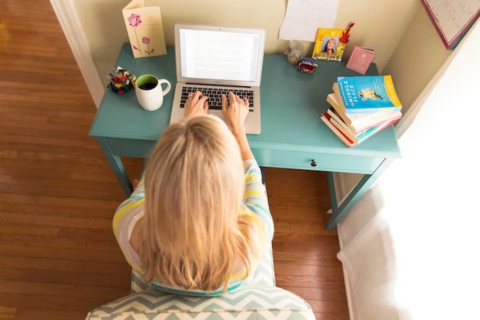 Angie Mizzell sitting at her desk typing into her laptop