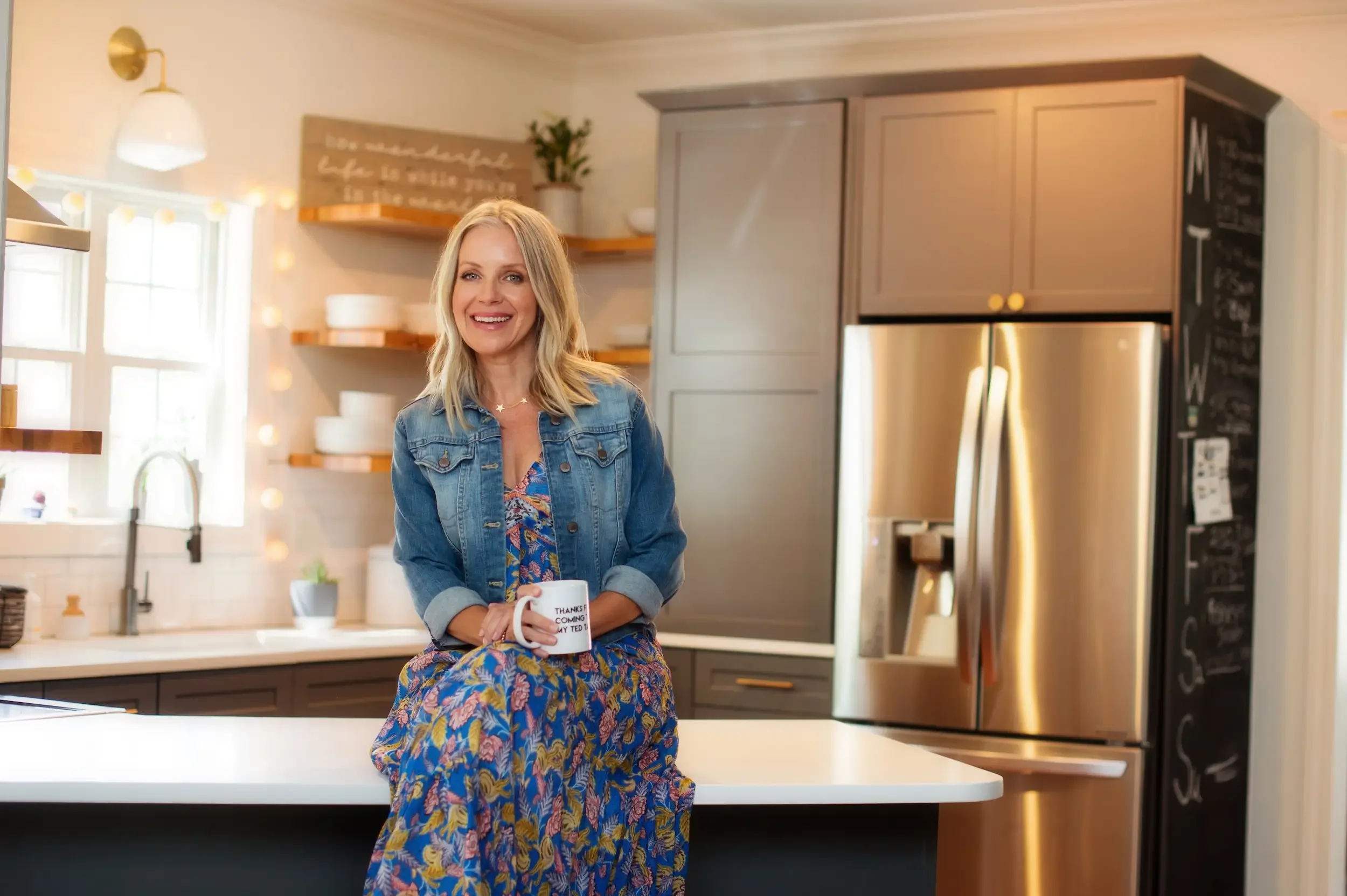 Angie Mizzell in her kitchen with a coffee cup facing the camera smiling.