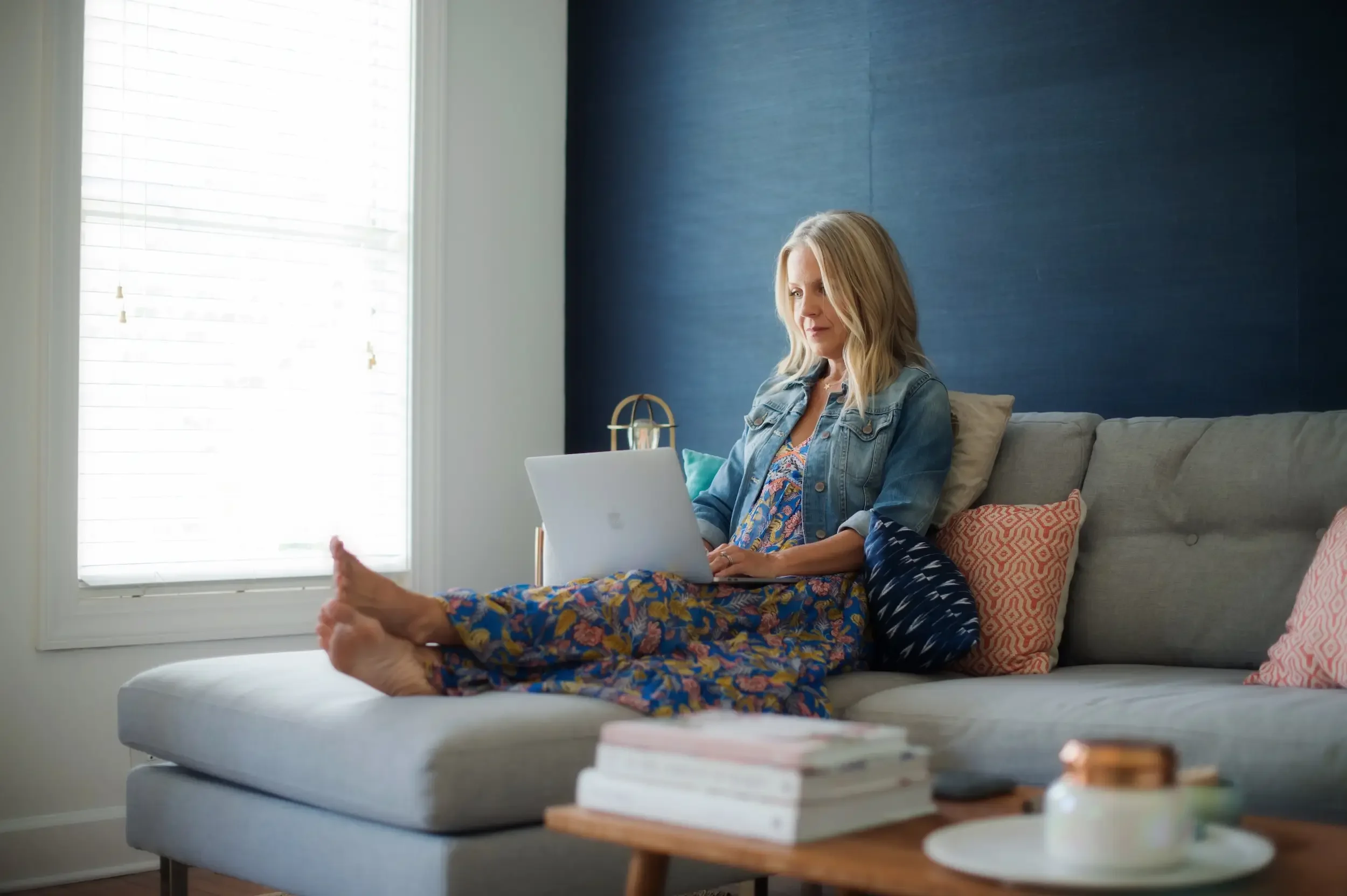 Angie Mizzell in her home office on the sofa with her laptop typing