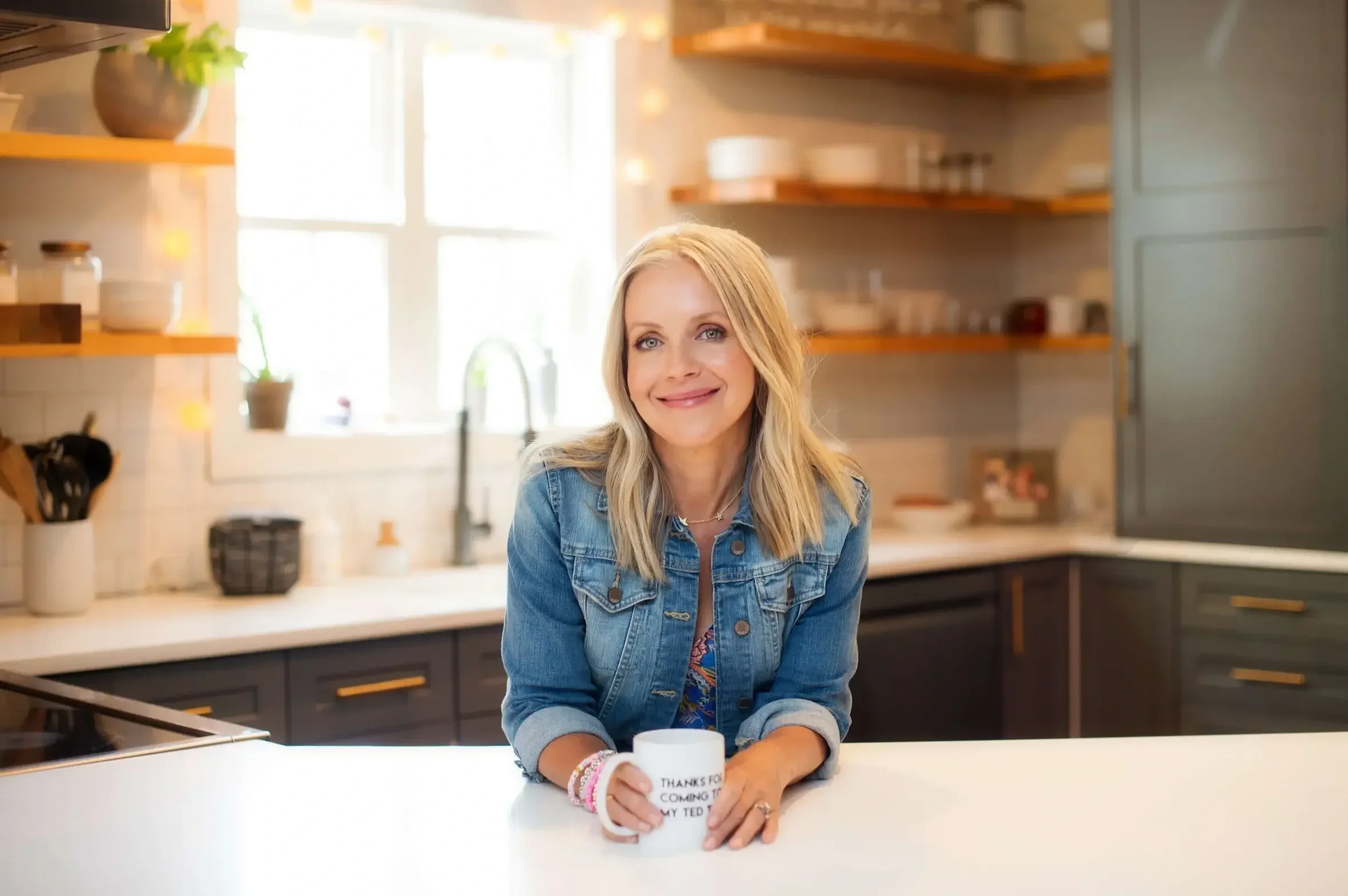 Angie Mizzell sitting at a kitchen counter, holding a mug.