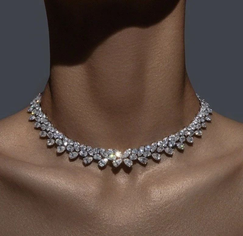 Close-up of a necklace with numerous sparkling diamonds worn on a person's neck.