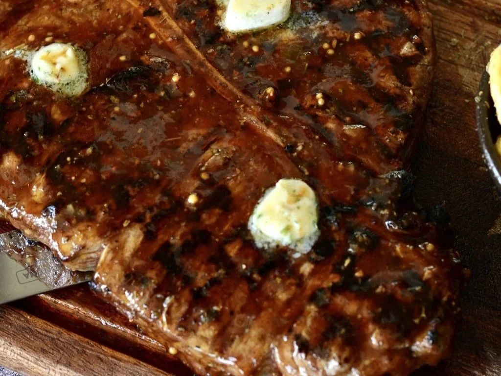 Barbecue ribs glazed with barbecue sauce, topped with dollops of butter.