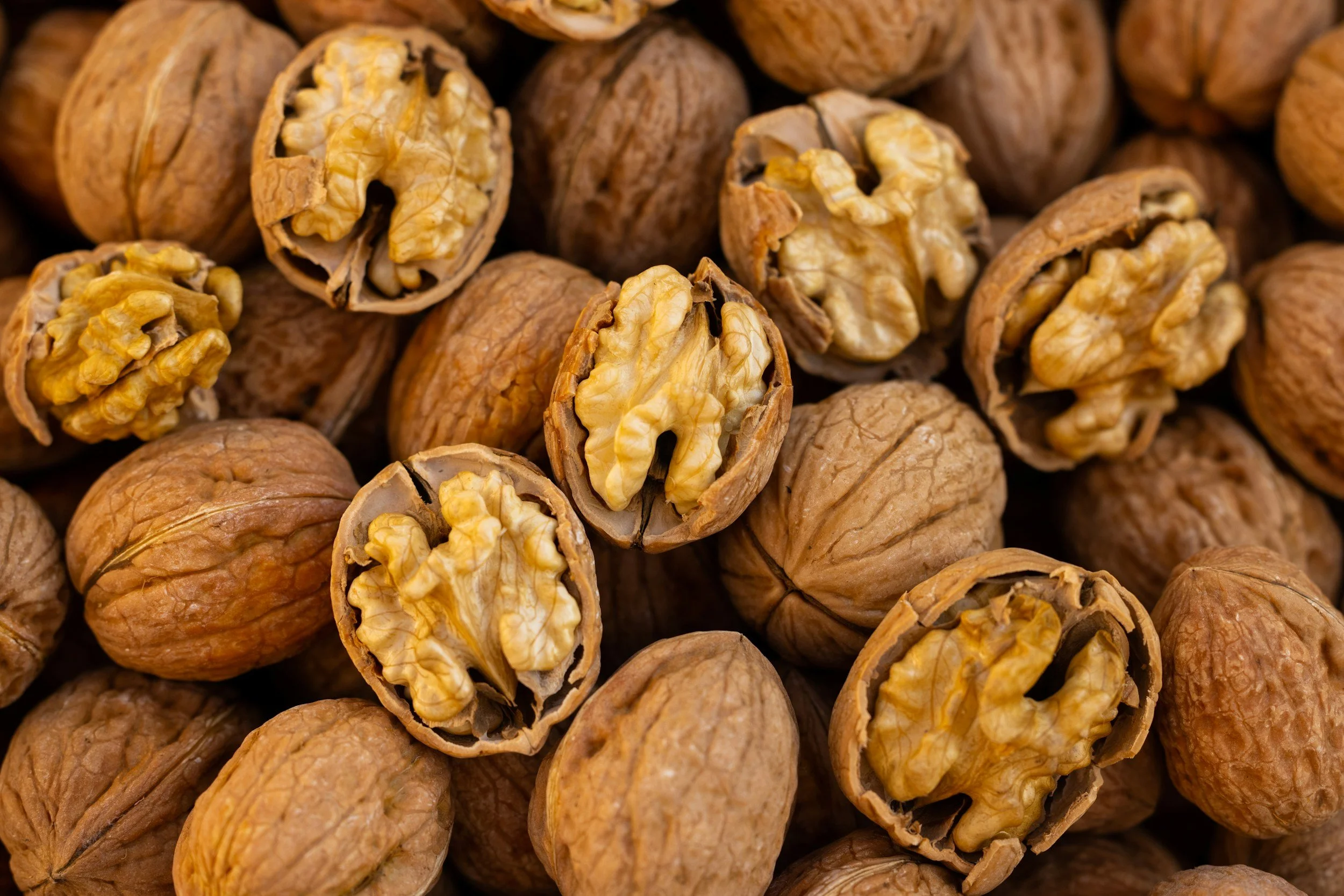 Close-up of whole and cracked open walnuts showing the nut inside.