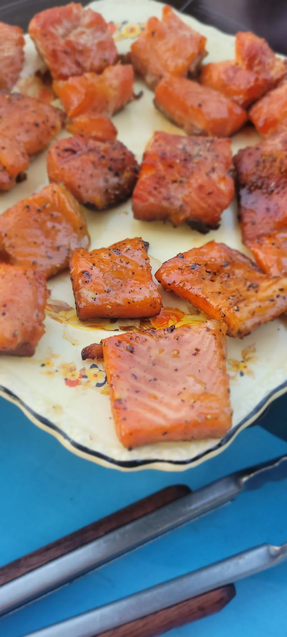 Close-up of smoked glazed salmon chunks on a decorative tray.