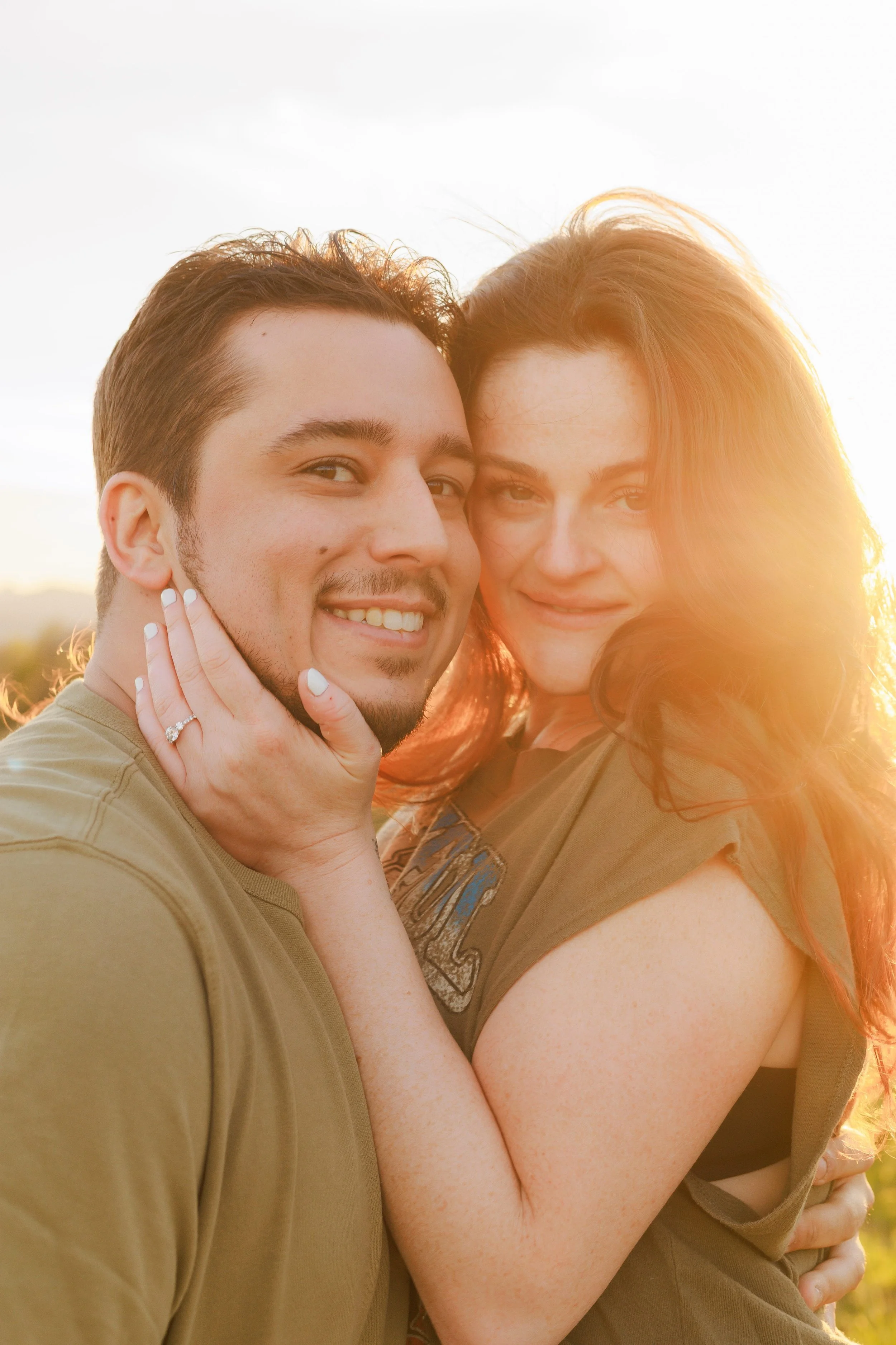 Couple standing side-by-side with their faces close together.